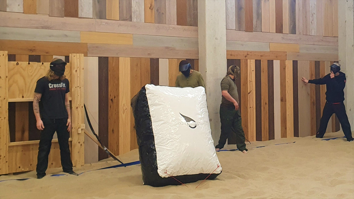 Vier mannen met een helm op staan langs de kant om te beginnen met Archery Tag.