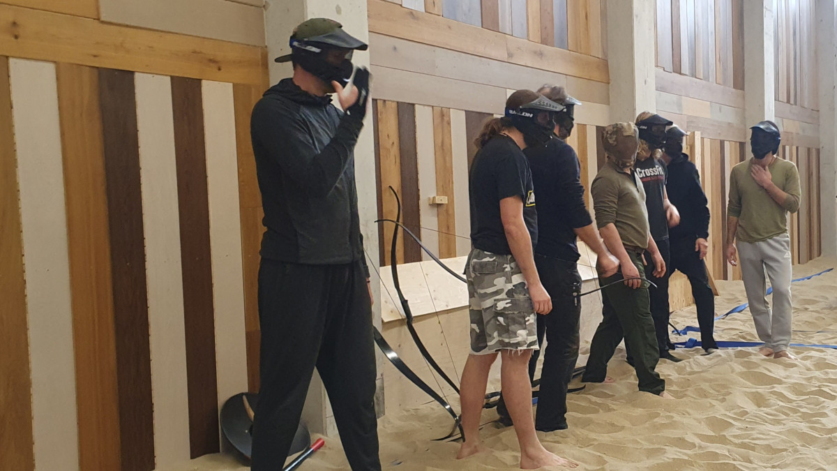 Een groep mannen staat langs de kant om te starten met Archery Tag.