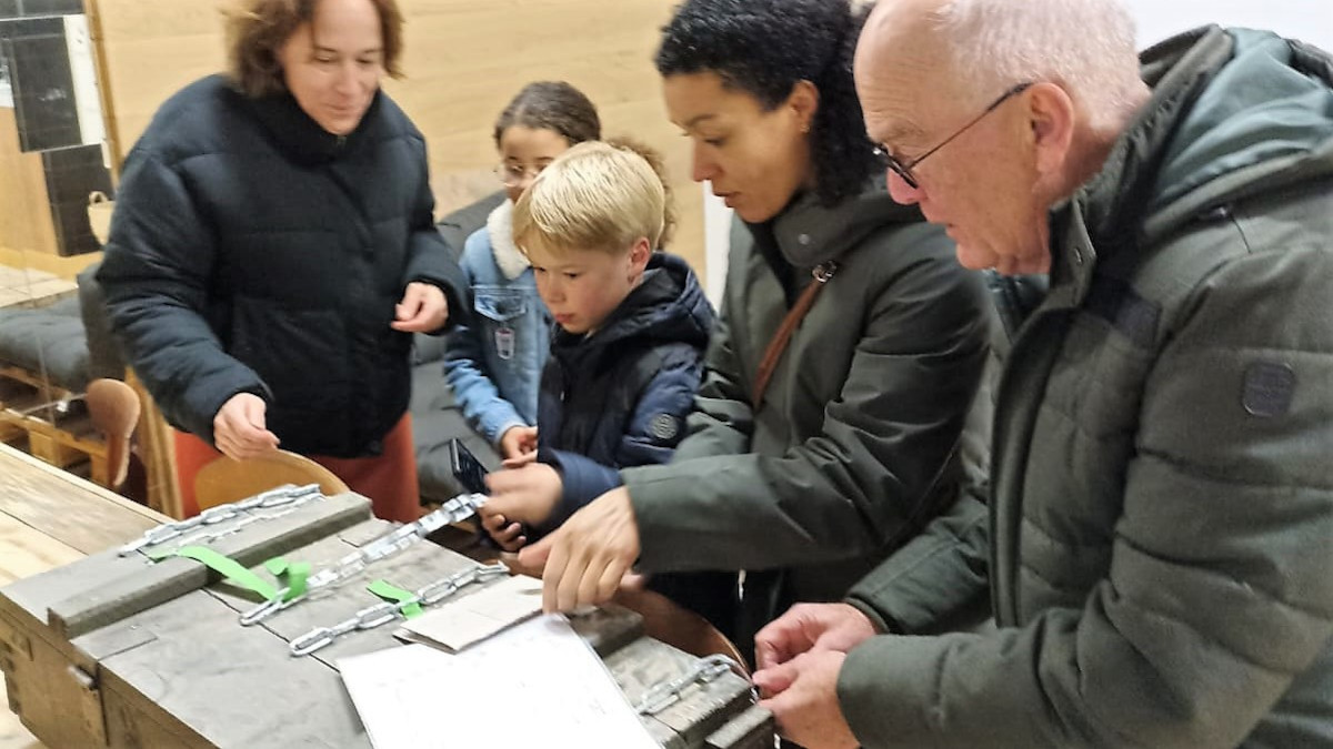 Een jongen probeert het cijferslot van de kist te openen.