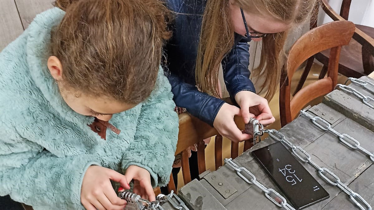 Twee meisjes proberen de cijfersloten van de kist te openen.