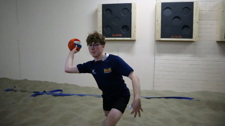 Een jongen met een dodgeball in zijn hand, klaar om deze naar het andere team te gooien.