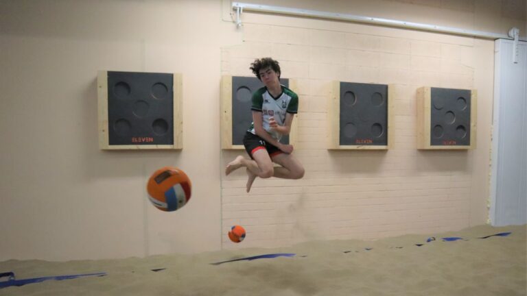 Een jongen heeft een sprong in de lucht gemaakt om twee dodgeballen te ontwijken.