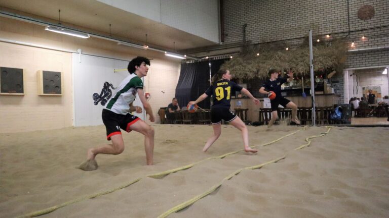Drie personen staan vlak bij de middenlijn om de dodgeballen naar het andere team te gooien.