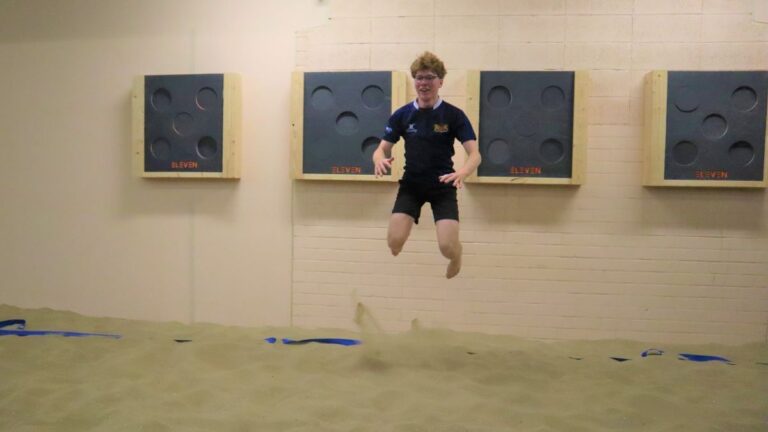 Een jongen hangt in de lucht nadat hij net omhoog heeft gesprongen om de dodgeballen te ontwijken.