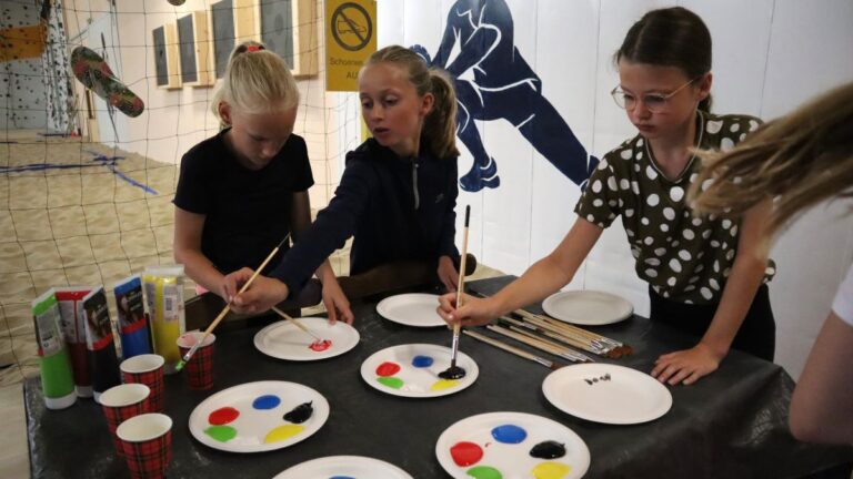 Drie meiden die aan het schilderen zijn tijdens het zomerkamp.