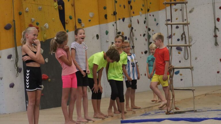 Een aantal kinderen staan langs de zijlijn en hebben onderling lol.