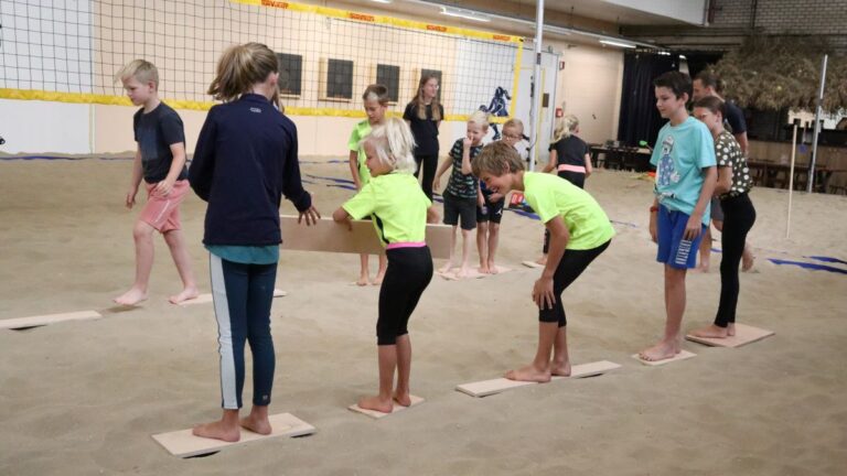 De kinderen staan op een plank en geven elkaar de volgende plank door om op te staan.