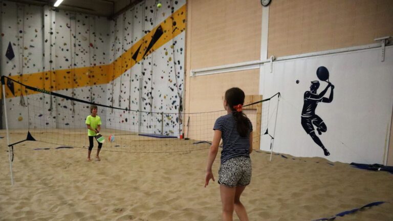 Een jongen en een meisje spelen samen beachtennis.