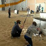 Twee jongens schuilen achter de bunker tijdens Archery Tag voor Scholen en maken zich klaar om te schieten.