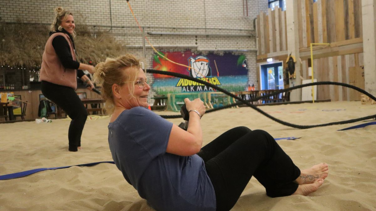 Circuittraining tijdens bootcamp. Iemand zwaait met touwen en een ander doet buikspieroefeningen.