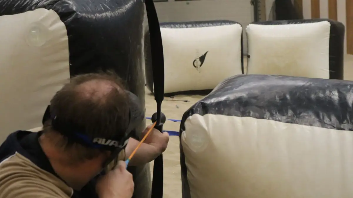 Een man richt zijn pijl tussen de obstakels door tijdens Archery Tag.