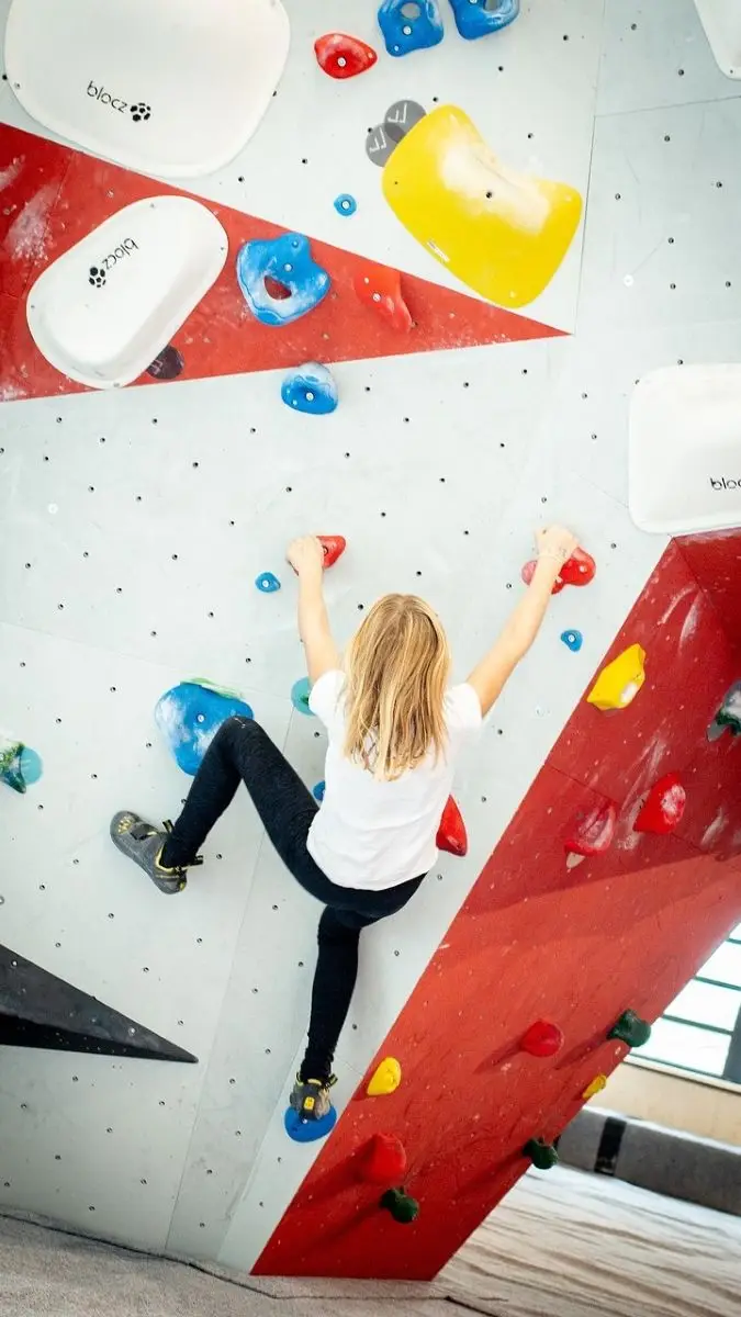 boulderen-kan-je-alleen-doen Een meisje is aan het boulderen en probeert de route uit te klimmen.