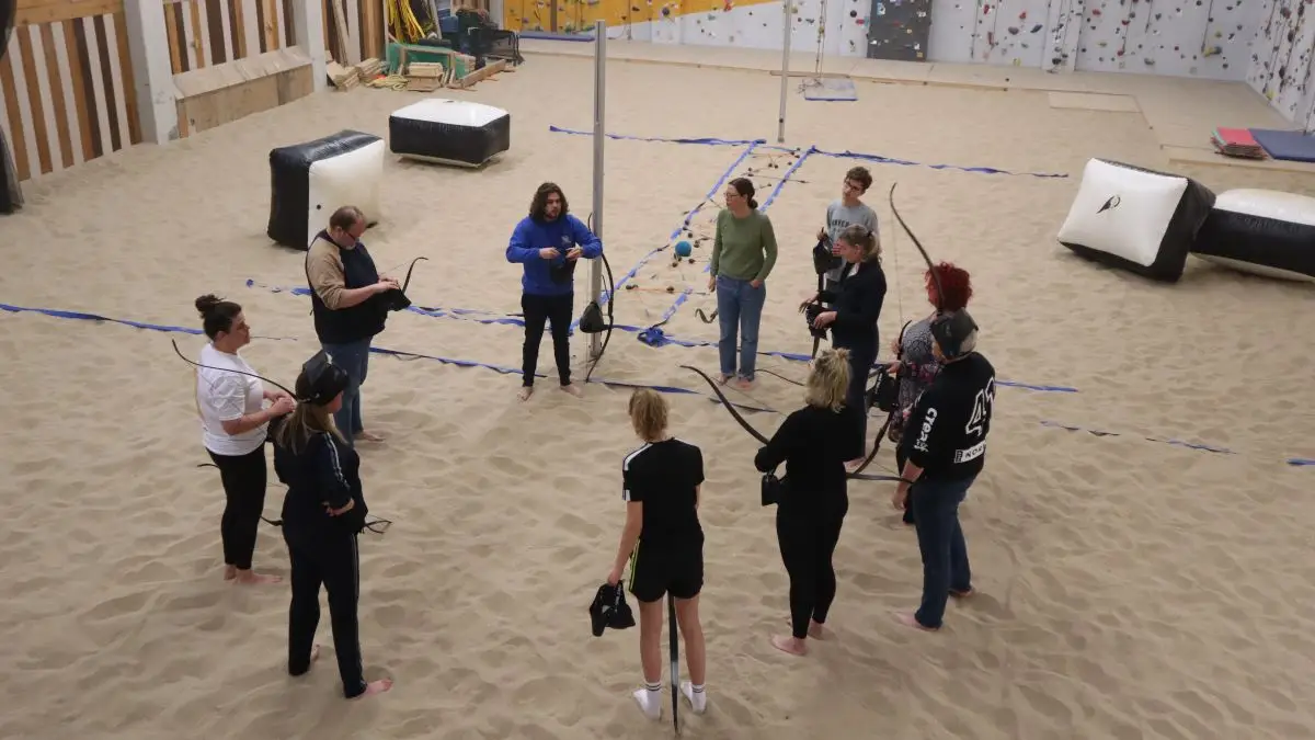 De instructeur legt de spelregels van Archery Tag uit aan de groep.
