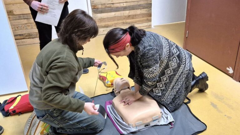 Twee personen oefenen een reanimatie op een oefenpop tijdens de BHV cursus bij Indoor Beach Alkmaar.