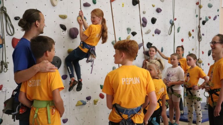 Aventuras Zomerkamp bij Indoor Beach Alkmaar. De groep kinderen gaan klimmen aan de klimwanden.
