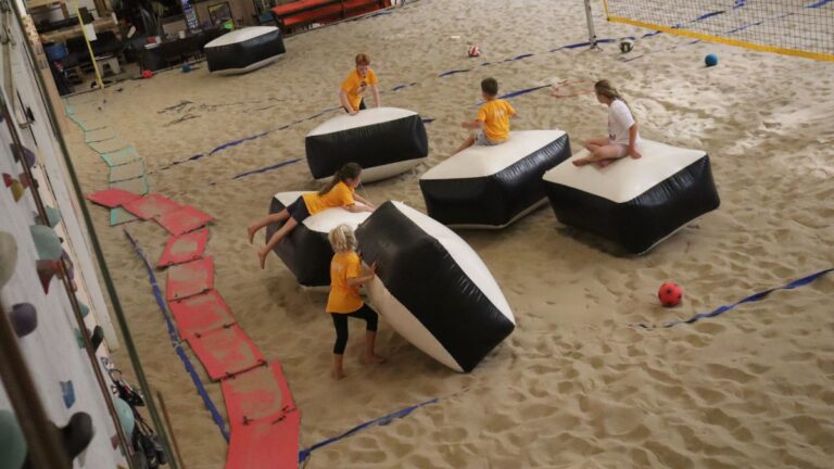 Aventuras Zomerkamp bij Indoor Beach Alkmaar. Een groep kinderen zitten op de kussens.