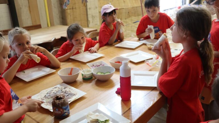 Aventuras Zomerkamp bij Indoor Beach Alkmaar. De kinderen lunchen samen aan tafel.
