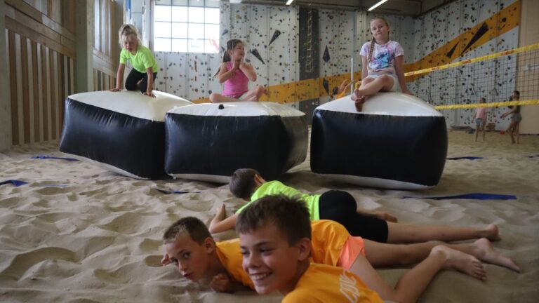 Aventuras Zomerkamp bij Indoor Beach Alkmaar. Drie meiden op kussen en drie jongens liggen op de grond ervoor.
