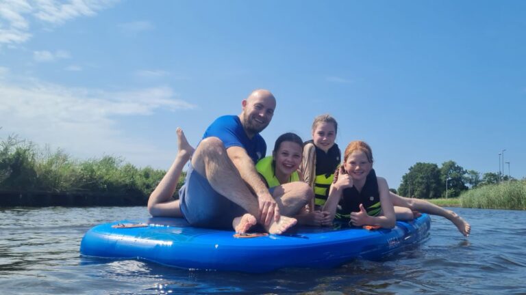 Aventuras Zomerkamp bij Indoor Beach Alkmaar. Mike zit met een aantal meiden op de sup.
