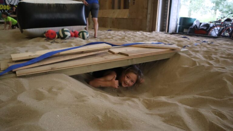 Aventuras Zomerkamp bij Indoor Beach Alkmaar. Een meisje schuilt in de bunker.