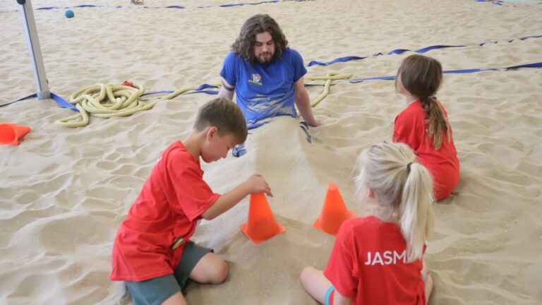 Aventuras Zomerkamp bij Indoor Beach Alkmaar. Preben wordt ingegraven.