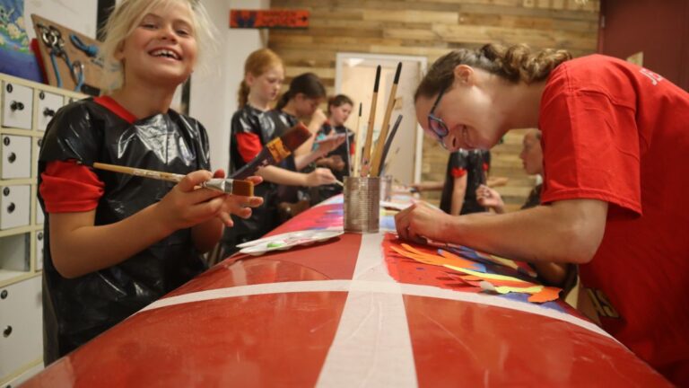 Aventuras Zomerkamp bij Indoor Beach Alkmaar. De meisjes beschilderen een surfplank.