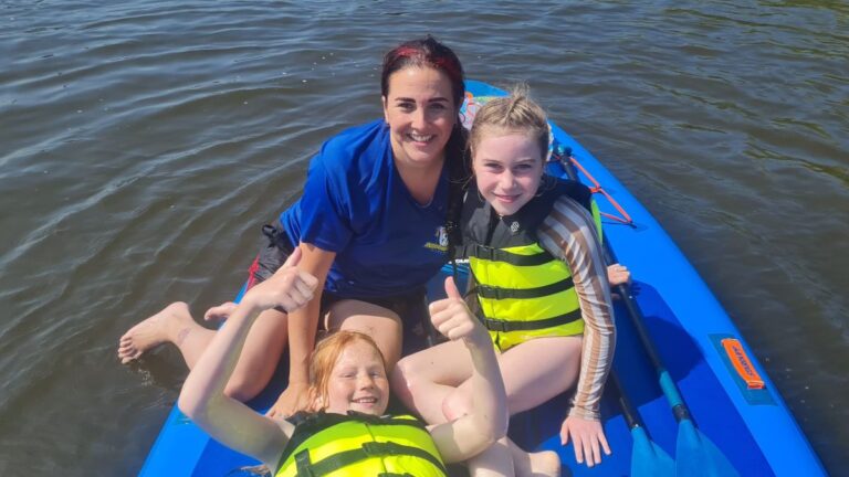 Aventuras Zomerkamp bij Indoor Beach Alkmaar. Tebrina zit met een aantal meiden op de sup.